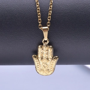 Macro d'un pendentif Main de Fatma dorée avec relief totem sur fond de cuir noir