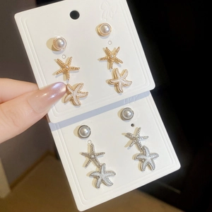 Detailed close-up of starfish and pearl stud earring sets with white enamel finish