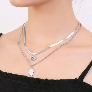 Double-layered silver necklace with Evil Eye and Hamsa Hand pendants on a female model