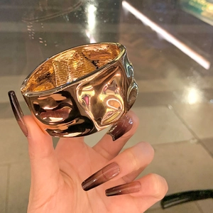 Goldenes Armband mit unregelmäßig gehämmerter Metallstruktur und rustikaler Knitteroptik