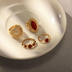 Detailed view of four vintage gold rings with red agate and zircons in a ceramic dish