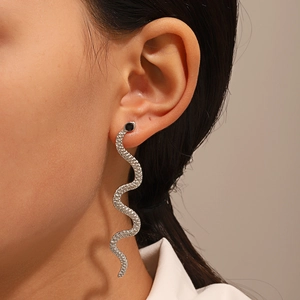 Detail shot of silver serpent earrings with textured scales and black gemstone eyes