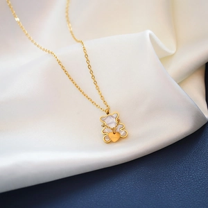 Macro detail of golden bear pendant with white mother-of-pearl and Love heart tag
