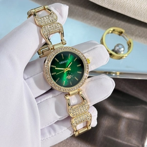 Détail d'une montre de luxe pour femme avec cadran vert et strass sur bracelet doré