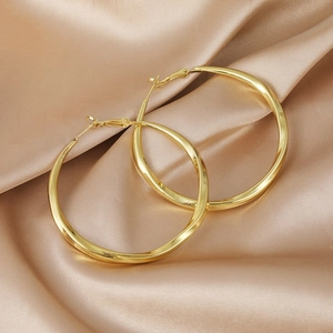 Minimalist golden twisted hoop earrings with metallic texture on elegant silk background