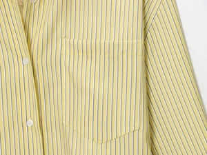 Detailed macro view of yellow striped poplin shirt with front pocket and white button