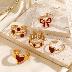 5-piece gold stainless steel ring set with red heart and bow designs on stone stand