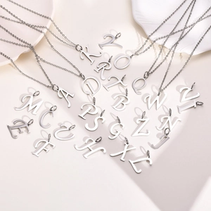Flat lay of multiple stainless steel alphabet pendant necklaces on a decorative plate