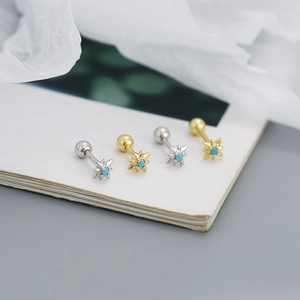 Macro shot of silver and gold eight-pointed star screw back studs with turquoise beads
