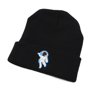 Close-up of black knitted beanie featuring detailed astronaut embroidery and texture
