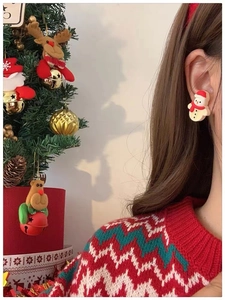 Détail de boucles d'oreilles bonhomme de neige avec écharpe rouge sur fond de Noël