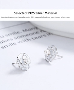 Macro detail of 925 silver camellia earrings with white enamel and center pearl inlay