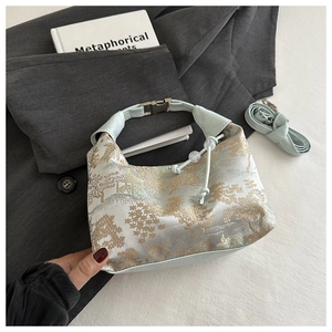 Detail of light cyan embroidered handbag with golden silk landscape patterns and strap