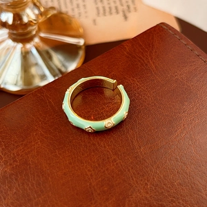 Dettaglio dell'anello fiore in smalto verde menta con interno dorato su pelle testurizzata