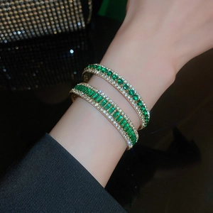 Close-up of emerald style bracelets with gold trim and crystal inlay on model wrist
