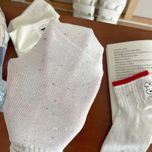 Close-up of white mesh knit socks with colorful polka dots and cute dog embroidery