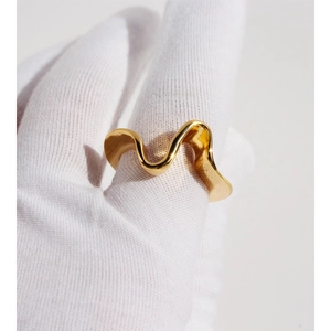 Minimalist gold plated brass wavy ring with irregular geometric design on gloved hand