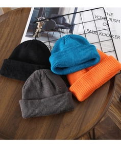 Pile of knitted beanies in black, blue, grey and orange with thick ribbed texture details