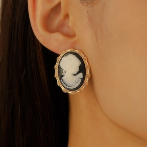 Close-up of vintage cameo earring with white relief on black base and gold metal frame