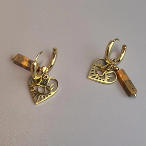 Detailed macro view of gold hoop earrings with heart eye charms and brown marble stones