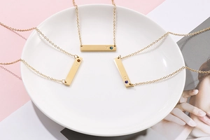 Detail of gold bar pendant necklace with heart engraving and small crystal inlay