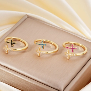 Detail of adjustable gold cross rings with zircon and colorful inlaid stones on silk