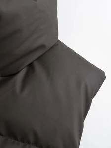 Detail of dark brown puffer vest featuring a stand collar and matte padded material