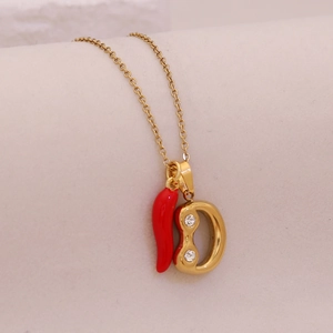 Macro view of gold necklace with red chili and diamond-studded D initial pendants