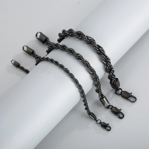Detailed view of three black stainless steel rope bracelets with lobster clasps on a white stand