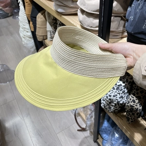 Detail of wide brim sun hat with yellow fabric stitching and beige woven texture