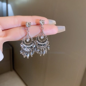 Detailed view of silver butterfly tassel earrings with black and clear crystals