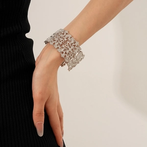 Detailed close-up of a silver hollow lace wide cuff bracelet on a model's wrist
