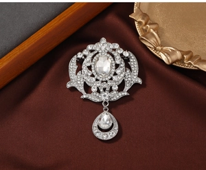 Close-up of vintage silver brooch with hollow patterns and sparkling crystals on brown silk