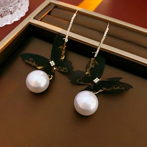 Detail of butterfly pearl earrings with lace wings and glittering diamond hook design