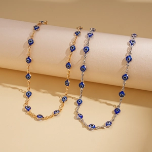 Detail of gold and silver Evil Eye necklaces displayed on minimalist beige pedestals