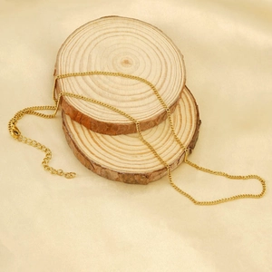 Close-up of gold curb chain necklace with lobster clasp on wooden display