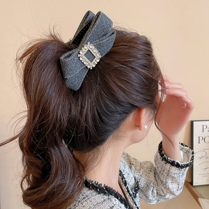Detailed view of a grey tweed bow hair claw clip with sparkling rhinestones on long hair