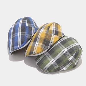 Détail de casquettes plates à carreaux colorés en bleu marine, jaune et vert chiné