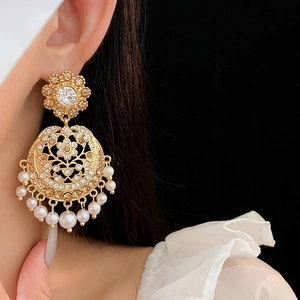 Detail of vintage gold earrings with sparkling crystals and elegant pearl drops