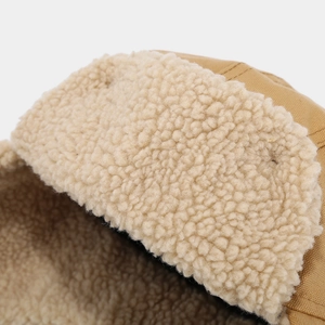 Detailed close-up of khaki canvas and thick white fleece lining on winter trapper hat