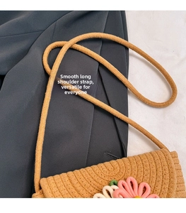 Detail of woven straw bucket bag featuring pink floral 3D accents and slim shoulder strap