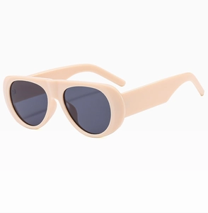 Detail view of cream-colored thick frames and dark lenses on oversized retro sunglasses