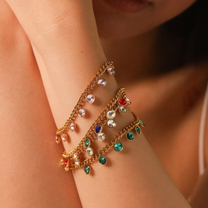 Three gold chain bracelets with colorful round zircons worn on arm for elegant style