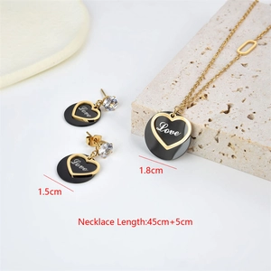 Detail of gold heart pendant necklace and earrings set with Love lettering and black inlay