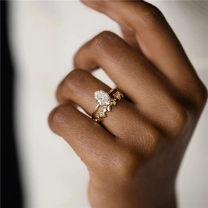 Close-up of golden ring set featuring oval clear gemstone and delicate leaf pattern