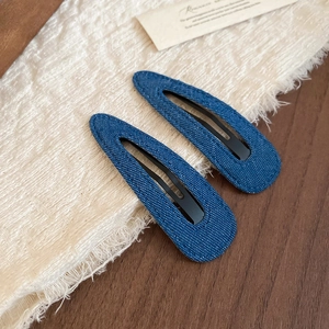 Detail of dark blue denim teardrop hair clips showing the textured fabric on fabric background