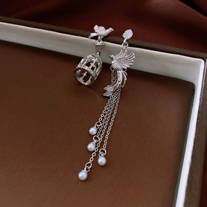 Detail of asymmetrical birdcage earrings with silver tassels and white pearls