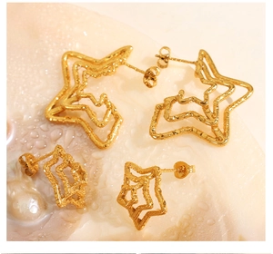 Macro view of golden textured spider web star earrings on a pearl water drop surface