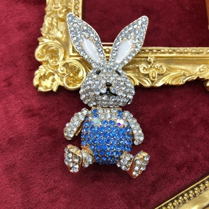 Exquisite rabbit brooch with sparkling blue and white rhinestones on red velvet background