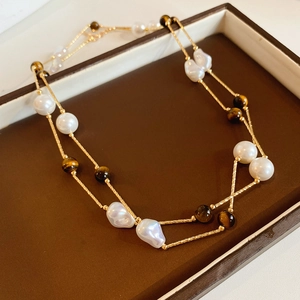 Detail of tiger eye stone and baroque pearl pendant on a double layer gold necklace